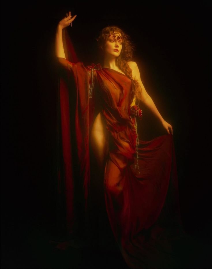 Femme drapée de rouge dans l'obscurité, éclairée d'une lumière chaude
